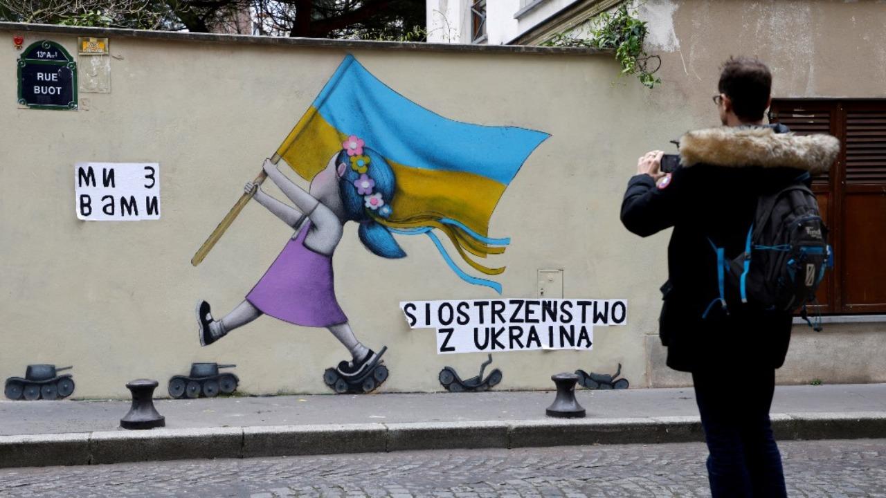 Berlin-based Colombian street artist Arte Vilu working on a mural featuring a Ukrainian woman in traditional dress, in Berlin on February 28, 2022. Photo: AFP